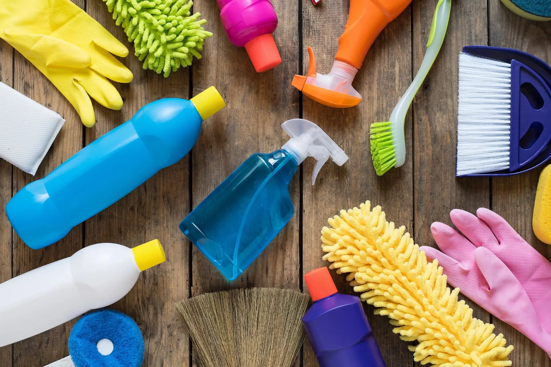 A wooden table topped with cleaning supplies and brushes.