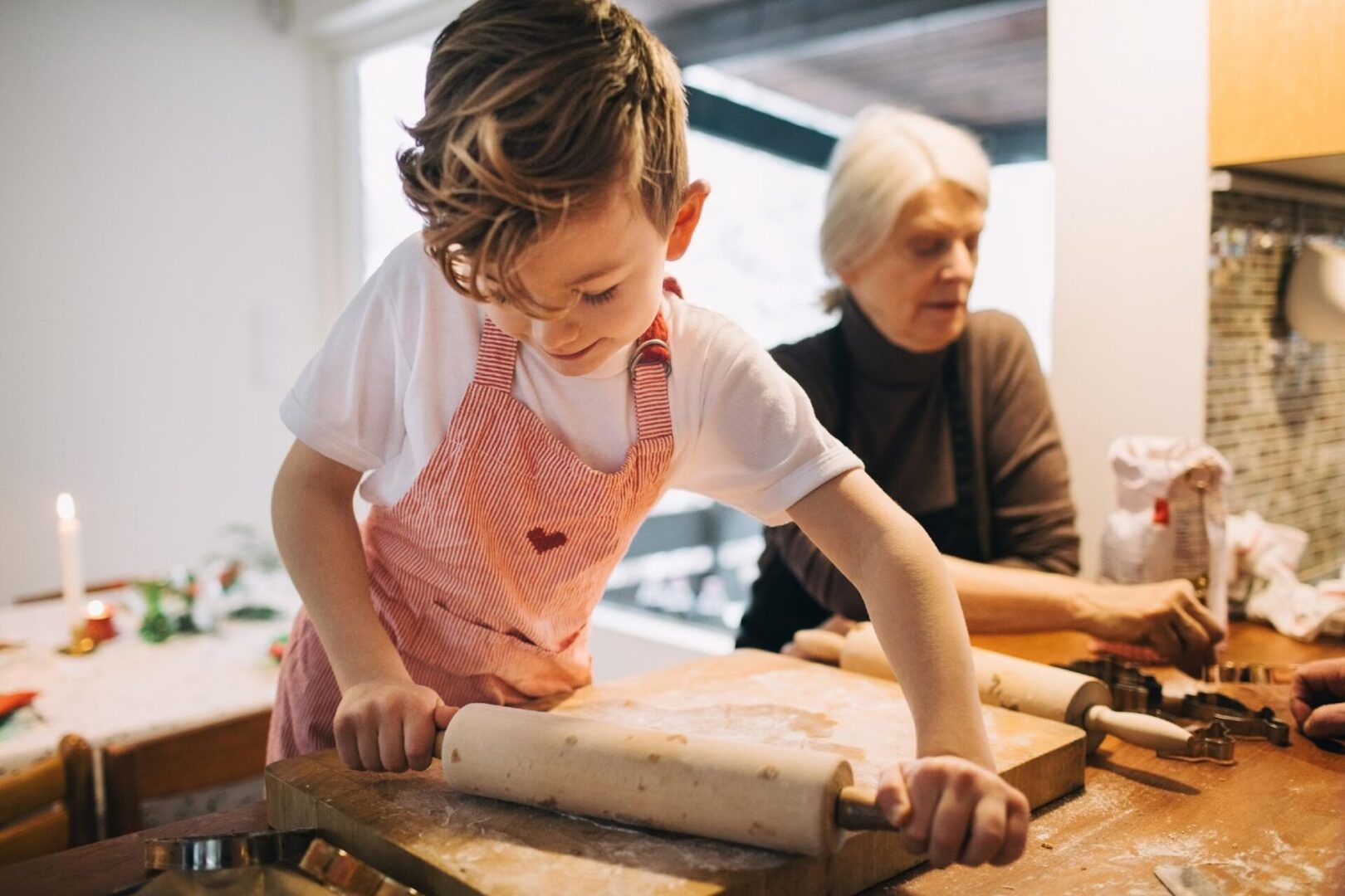 A young girl rolling dough on top of a wooden table.