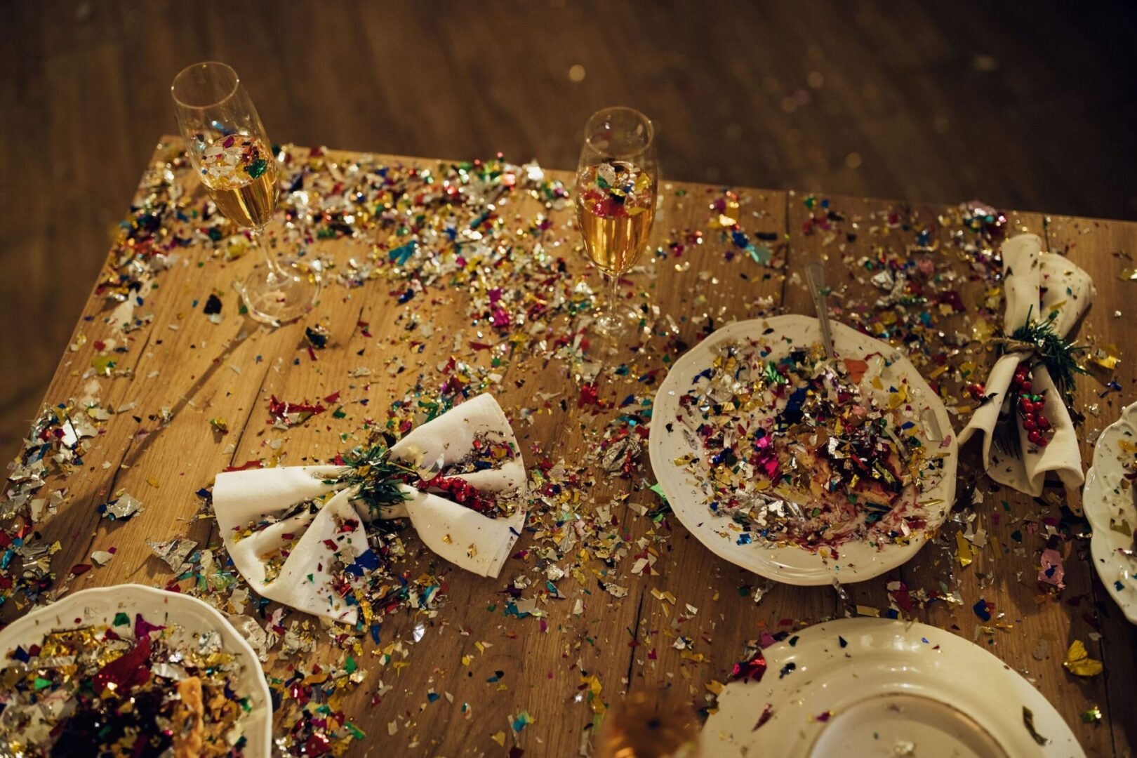 A table with plates and cups covered in confetti.