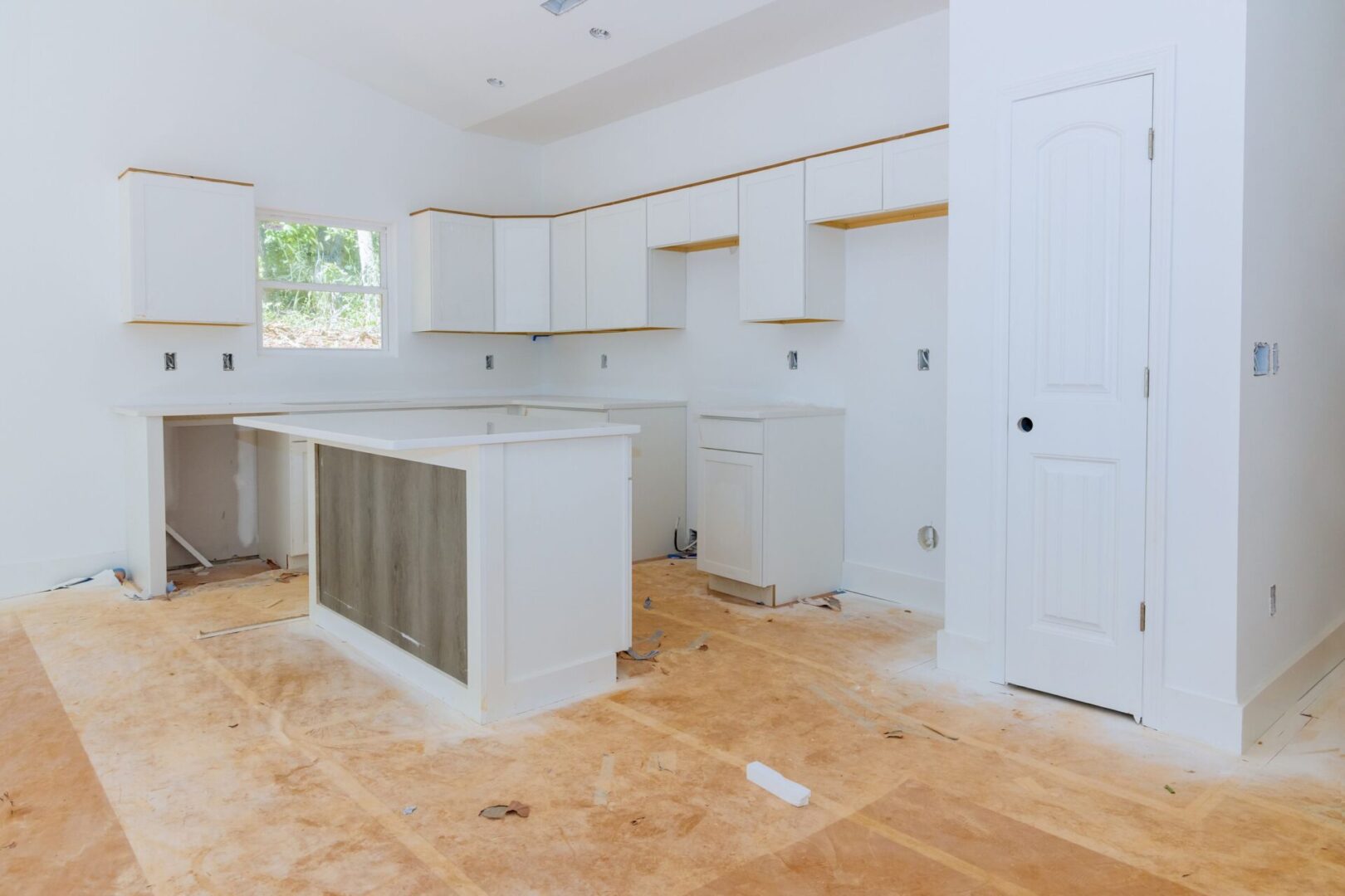 A kitchen with white cabinets and wood floors.