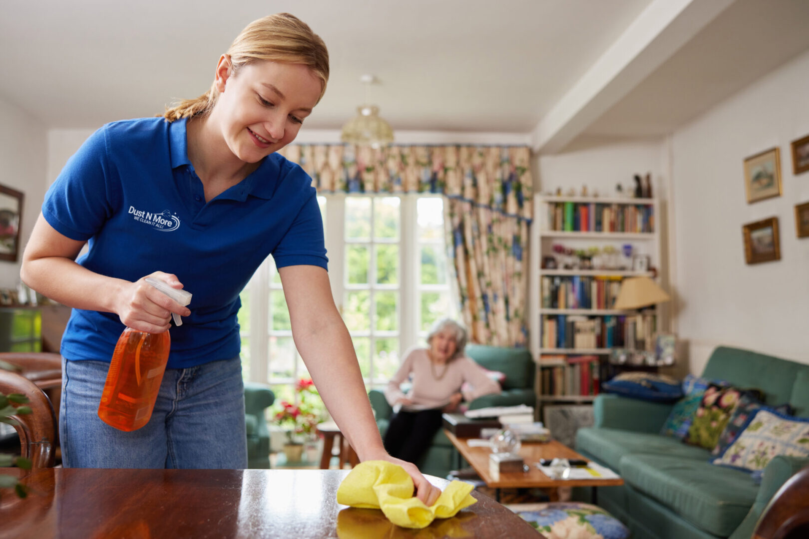 A woman is cleaning the table in her living room.